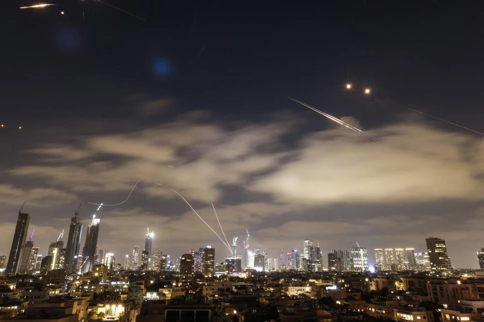 DEFENSA AÉREA. El sistema israelí para interceptar misiles iraníes ilumina la noche de la ciudad de Tel Aviv, en una escalada sin precedentes.  