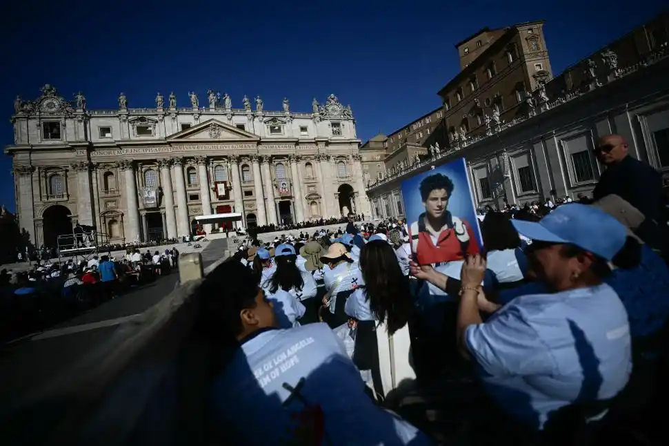 SANTO. Uno de los fieles presentes en la plaza San Pedro en el Vaticano sostiene la foto de Carlo Acutis, durante la misa de su canonización.