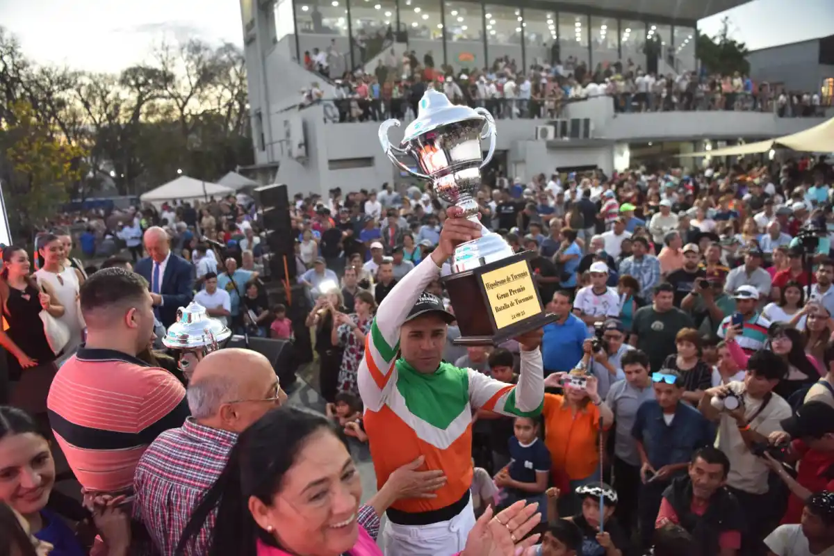 GRAN CONVOCATORIA. El jockey Facundo Morán levanta la copa del Batalla; atrás una multitud vibra con el emocionante momento.