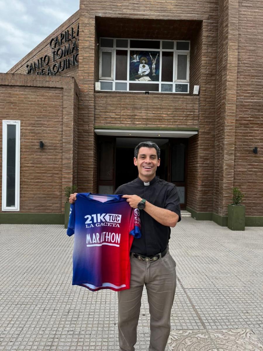 CON ORGULLO. El padre Larrosa posa con la camiseta de los 21k de LA GACETA frente a la Iglesia de la comunidad Fasta.