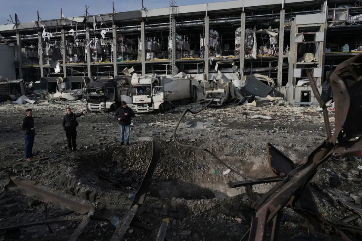 CRÁTER. Policías ucranianos inspeccionan el pozo que dejó una bomba rusa en el estacionamiento de un supermercado, en las afueras de Kiev.