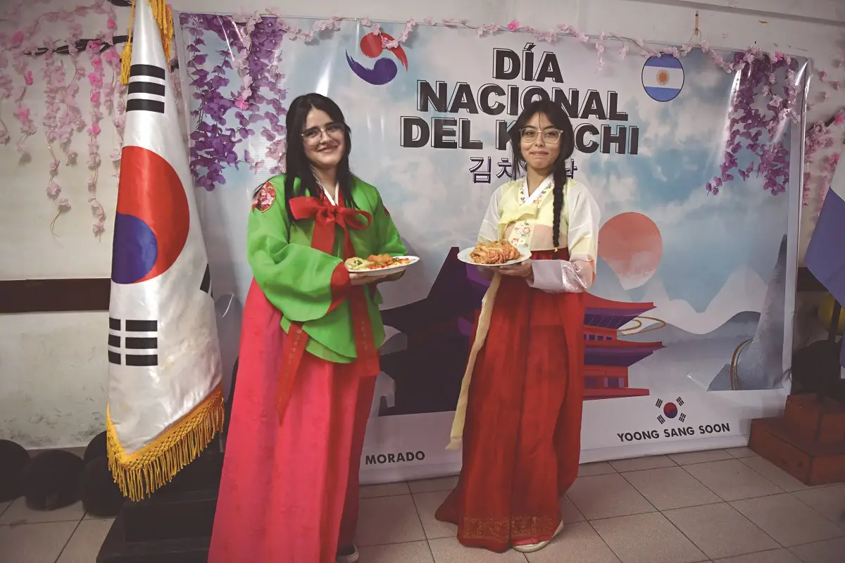 ANTONELLA Y CARLA. Las adolescentes posan con vestidos tradicionales llamados hanboks y comidas típicas coreanas. Carla tiene un plato de kimchi.