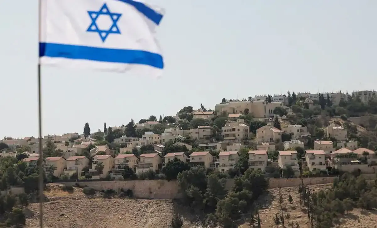 Una bandera israelí ondea con el asentamiento de Maale Adumim al fondo.