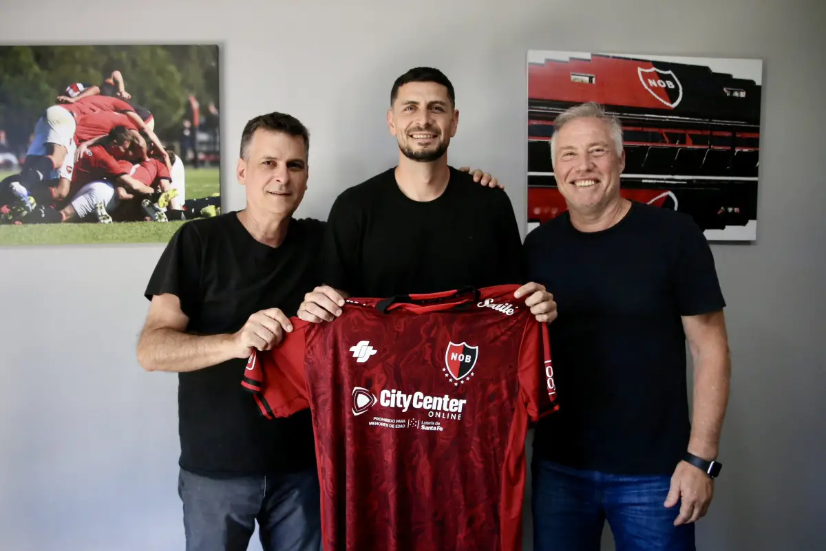 Arias posa con la camiseta rojinegra tras sellar su llegada a Newell’s, acompañado por dirigentes. |  Foto: @Newell's en X