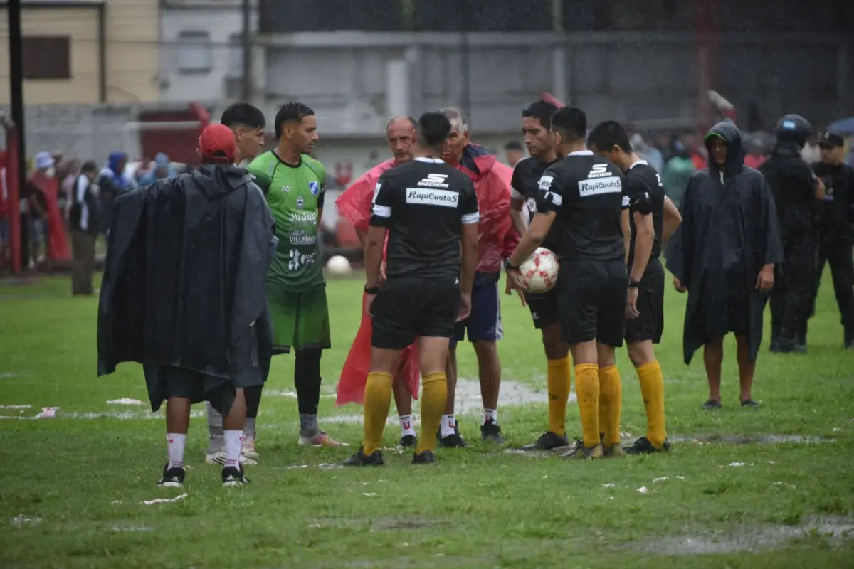 EL MOMENTO DE LA DECISIÓN. La terna arbitral se reúne con los capitanes de cada equipo para evaluar la continuidad del partido. Finalmente, se decidió postergar el partido para mañana desde las 17.