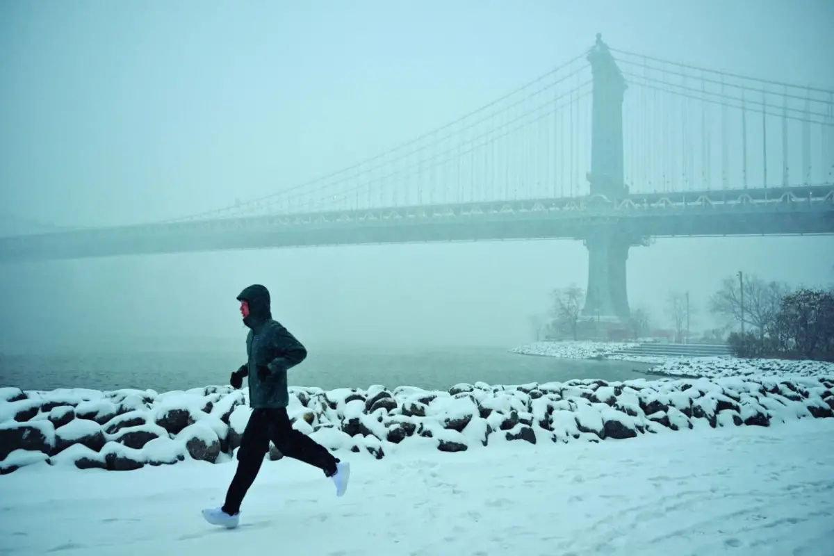 EJERCICIOS. Un hombre corre en la nieve cerca del puente de Manhattan, en el distrito de Brooklyn. afp