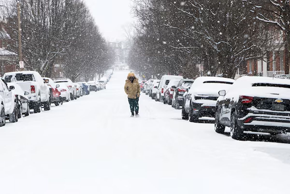 Una persona camina en soledad por una calle residencial cubierta de nieve en St. Louis, Missouri 