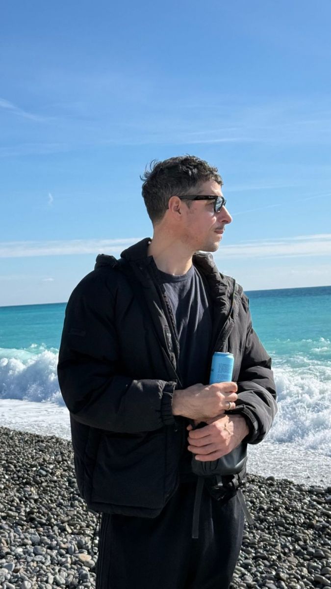 Esteban Lamothe posa rente al mar turquesa de la Costa Azul con gafas de sol y look abrigado total black. 