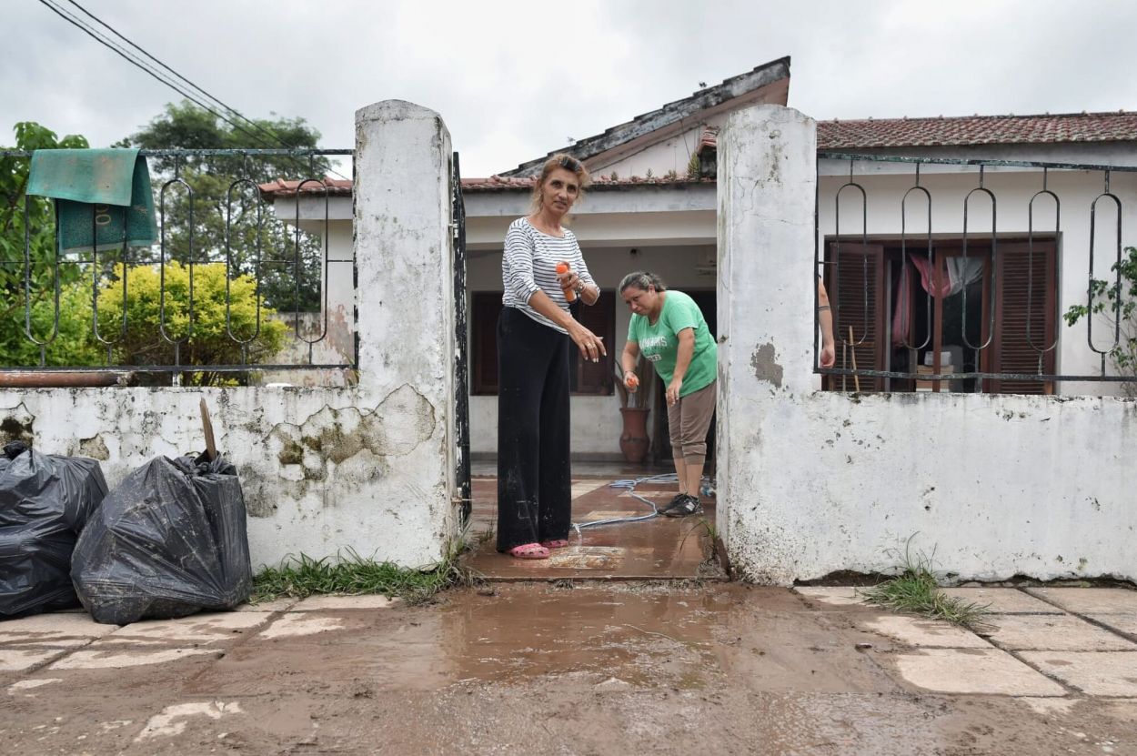 LO QUE QUEDÓ. Vecinos de Villa Belgrano retiran el agua de sus viviendas tras el desborde de los cursos de agua durante la madrugada.