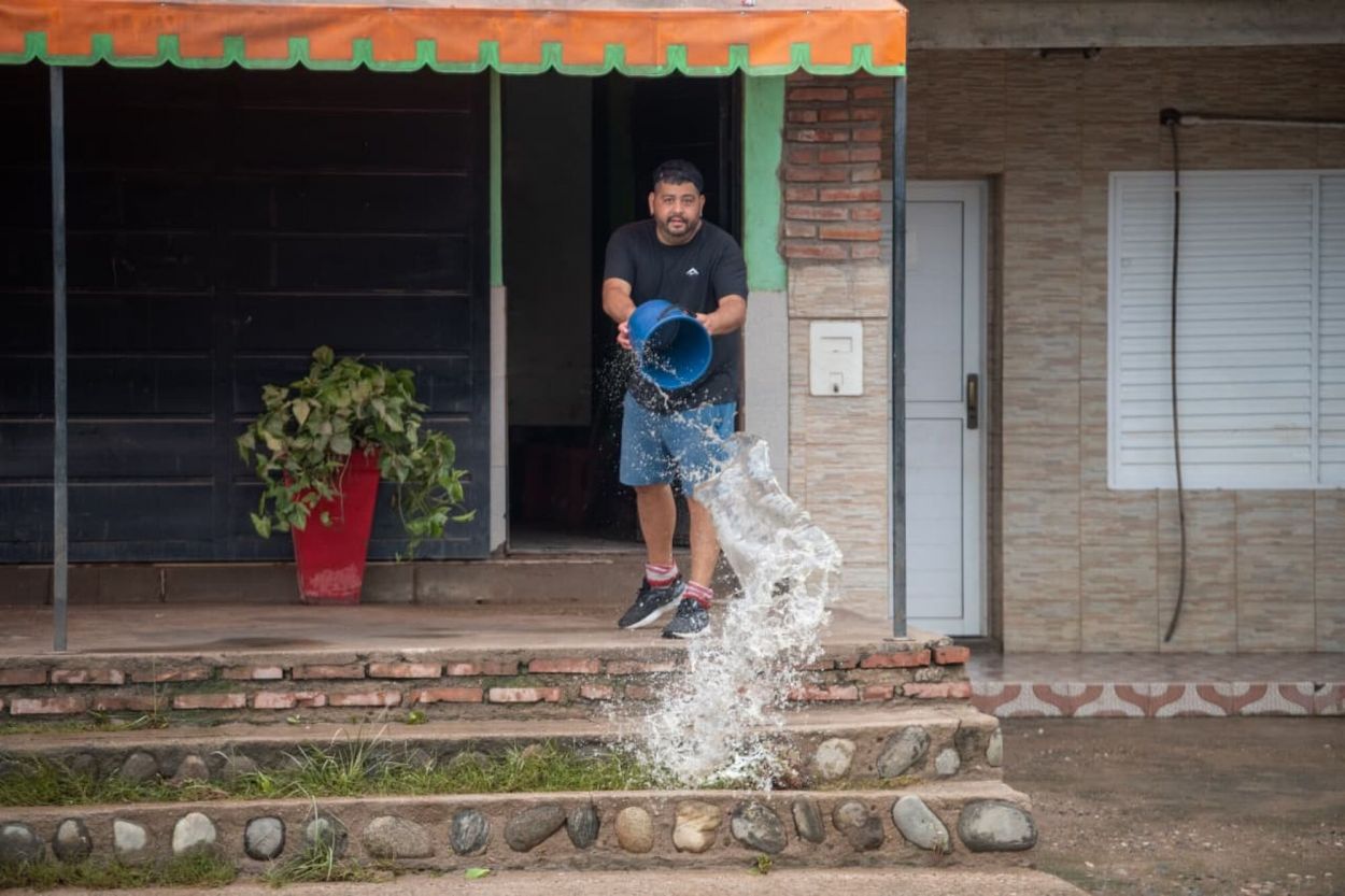 LOS RESTOS. Con baldes, los vecinos intentan sacar el agua de sus casas.
