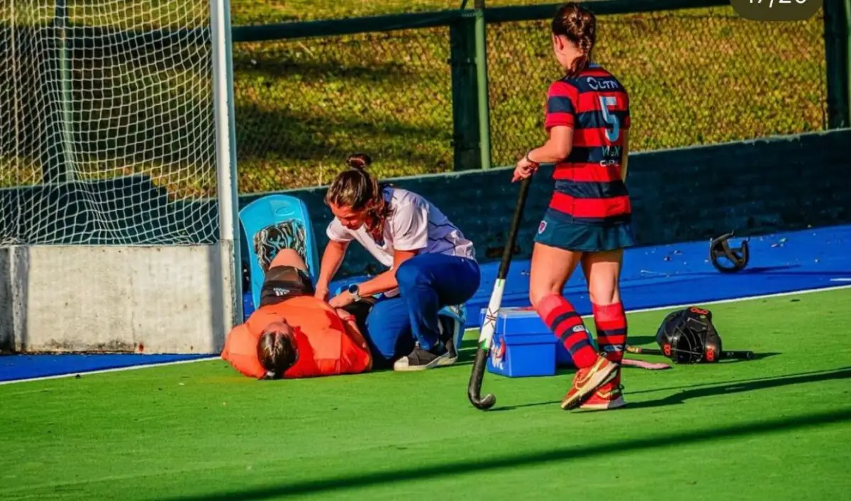 PROFESIÓN Y DEDICACIÓN. Martina Peralta asiste a la arquera lesionada durante un partido de Tucumán Rugby. La delantera acaba de recibirse de médica y combina las guardias con su pasión por el hockey.