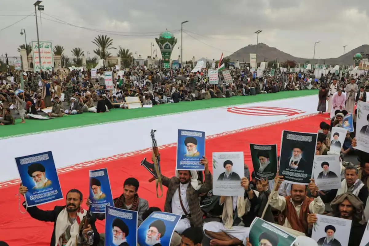 Hutíes sostienen carteles del líder supremo de Irán, junto a una enorme bandera iraní.