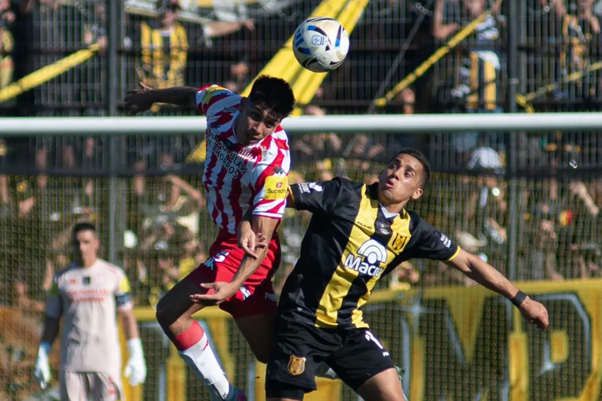 LUCHA AÉREA. Laureano Rodríguez intenta rechazar un balón ante la carga del volante Nicolás Barrientos.