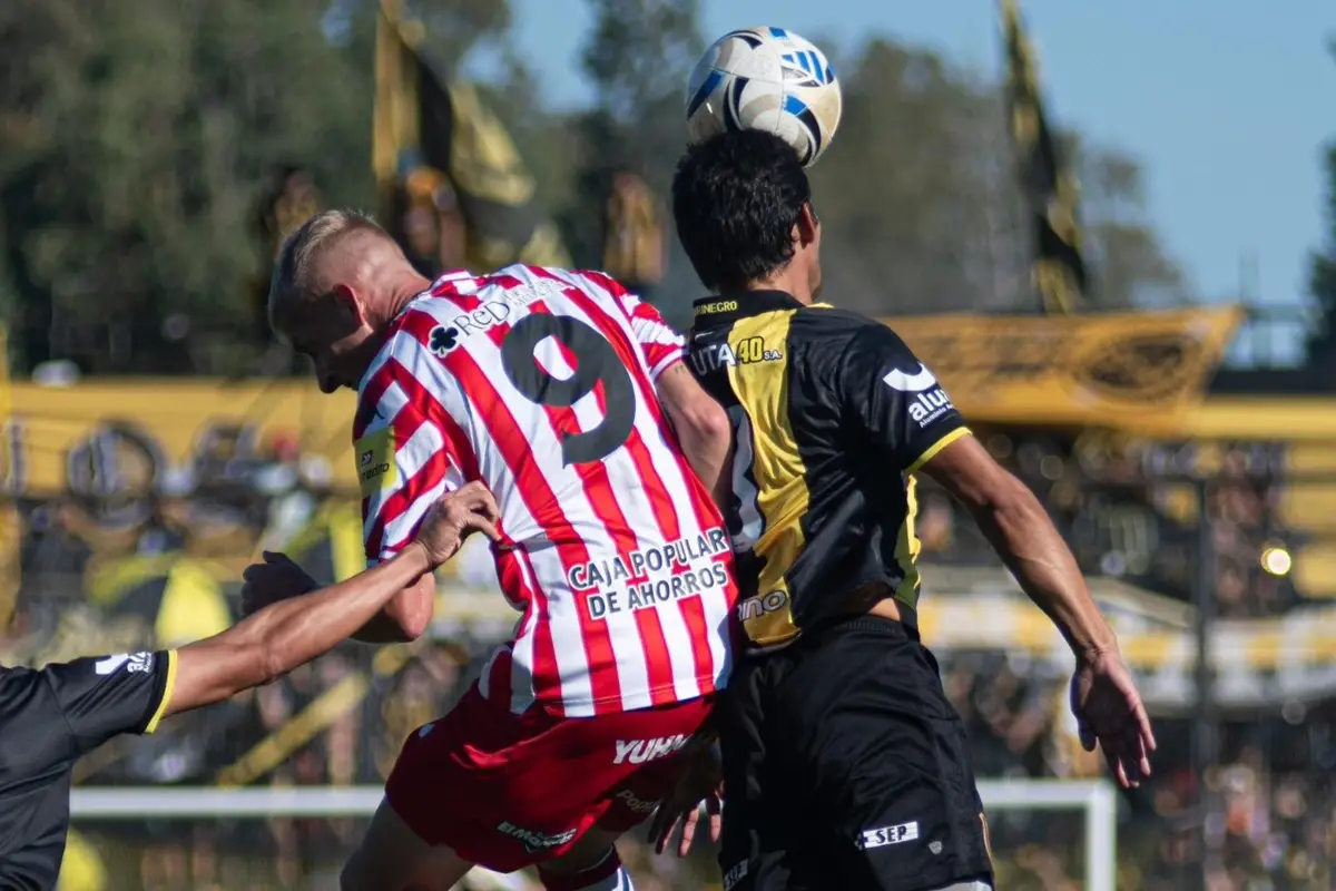 POR LOS AIRES. Diellos disputa una dividida con Marcelo Meli durante el empate entre San Martín y Deportivo Madryn.