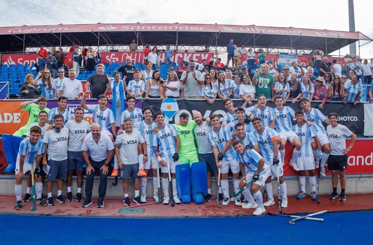 UNIÓN. El plantel argentino posa junto al cuerpo técnico y familiares tras la consagración, con medallas, banderas y la alegría desatada en la tribuna.