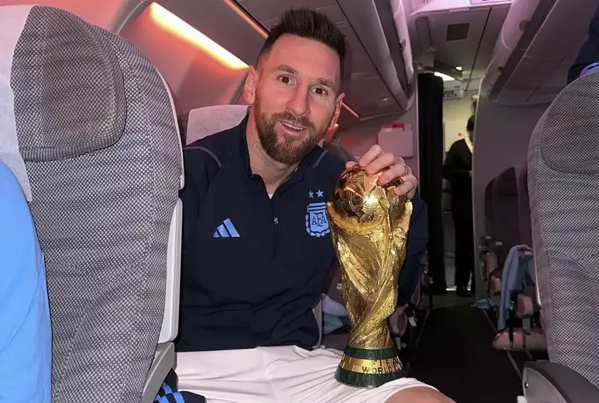 MOMENTO SOÑADO. Messi posa con la Copa del Mundo en el avión de regreso al país, luego de consagrarse en Qatar 2022.